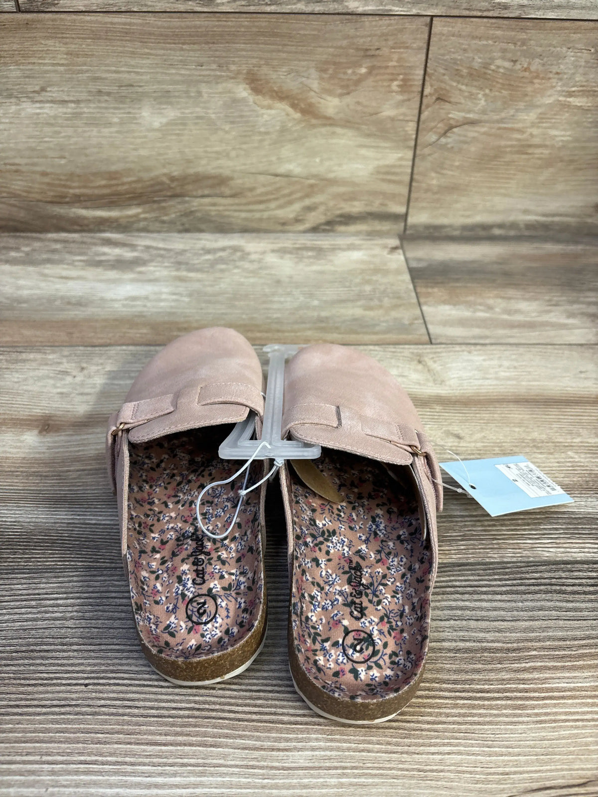 Top-down view of Cat & Jack Perry toddler clogs in blush showcasing floral printed insoles, cork footbed, and adjustable strap on wood background