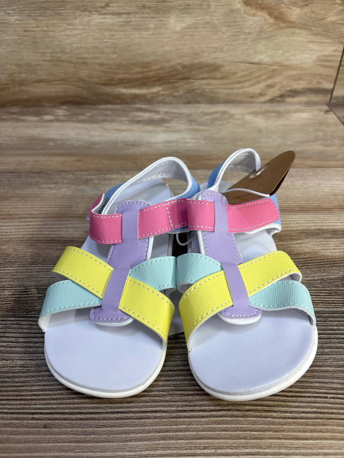 Front view of Shayna toddler sandals showcasing pastel multicolor Velcro straps and white footbed on wood background
