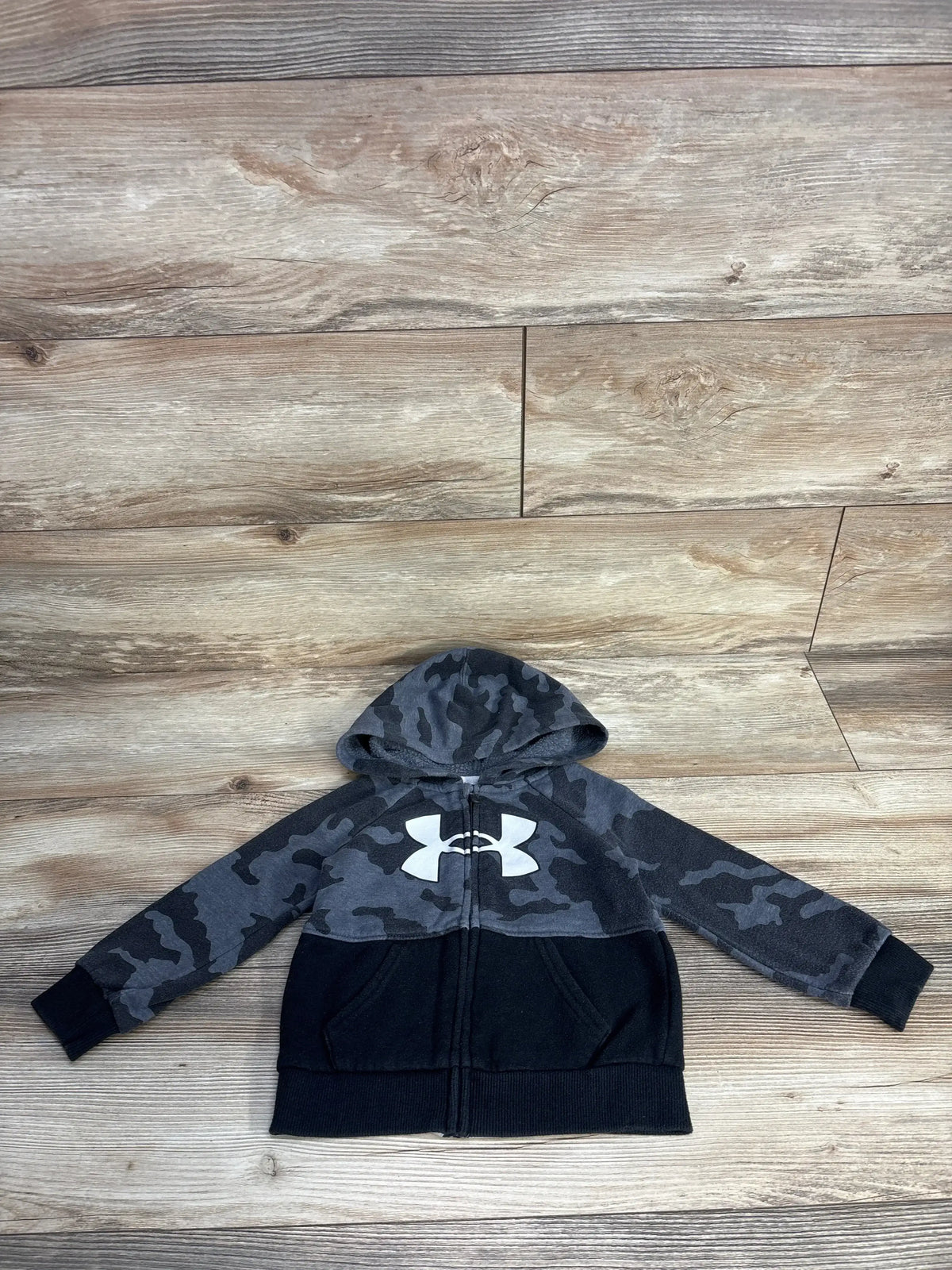 Kids black camo Under Armour zip hoodie on wood floor background