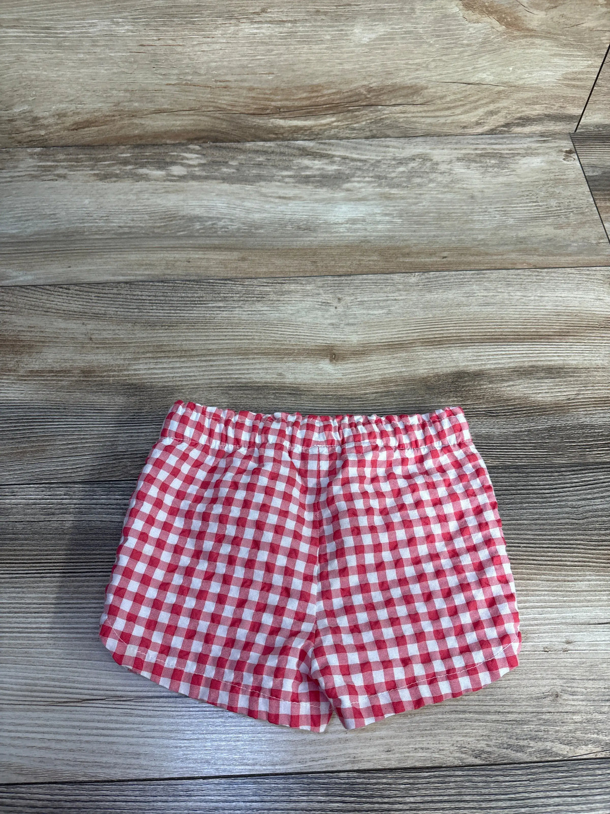 Front view of Cat & Jack red gingham shorts showcasing elastic waistband on a wood floor