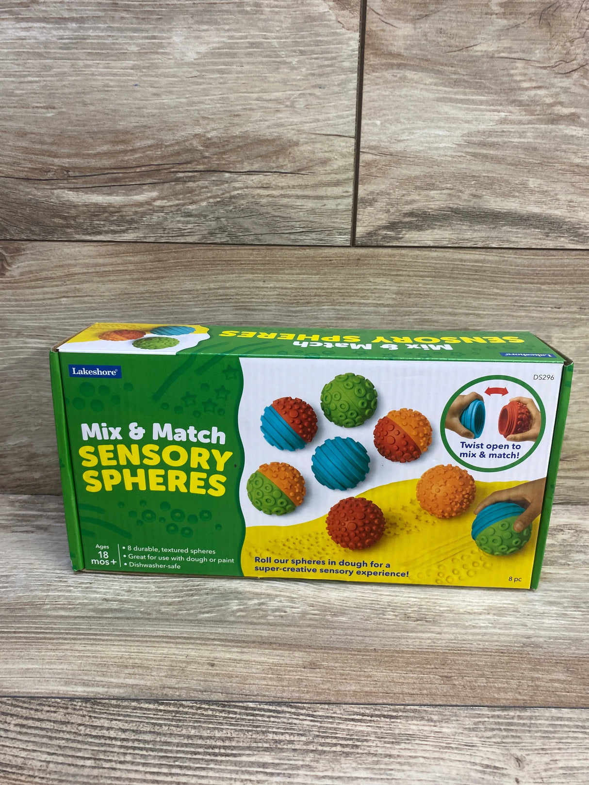 Front view of Lakeshore Mix & Match Sensory Spheres box showcasing colorful textured balls and twist-open mix feature on a wood floor background