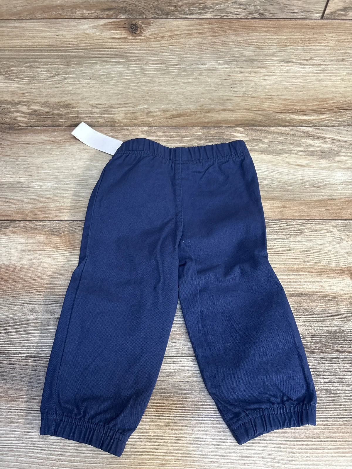 Navy blue kids joggers with elastic waist and cuffs, laid flat on wood floor