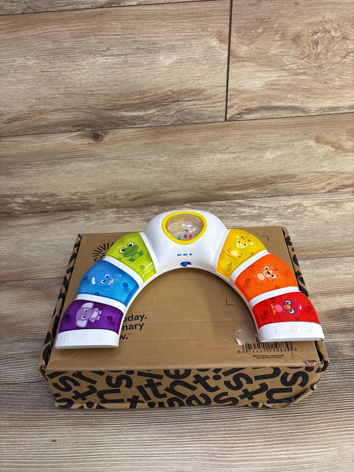 Angled top view of Baby Einstein Glow & Discover Light Bar showing rainbow animal music buttons and central spinning light on a cardboard box