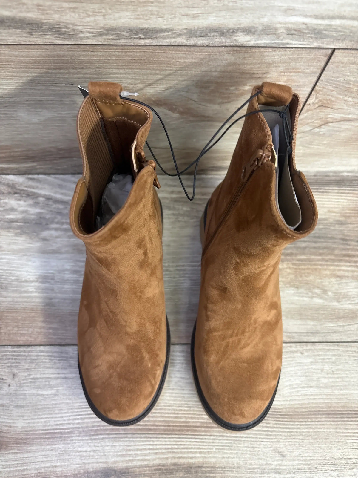 Pair of brown suede children's boots with side zippers on wood floor