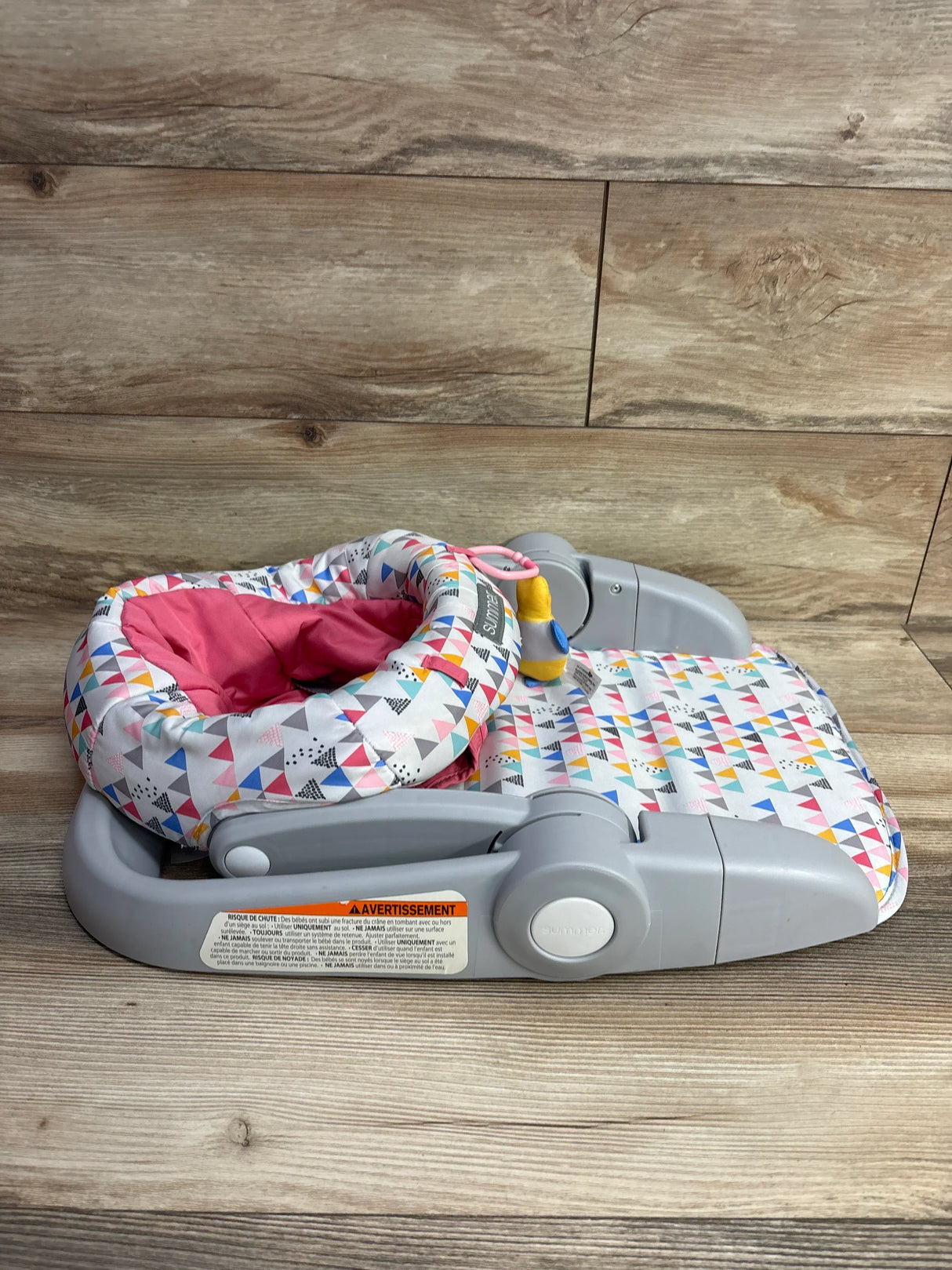 Folded multi-color patterned baby floor seat with pink inner cushion and gray plastic frame