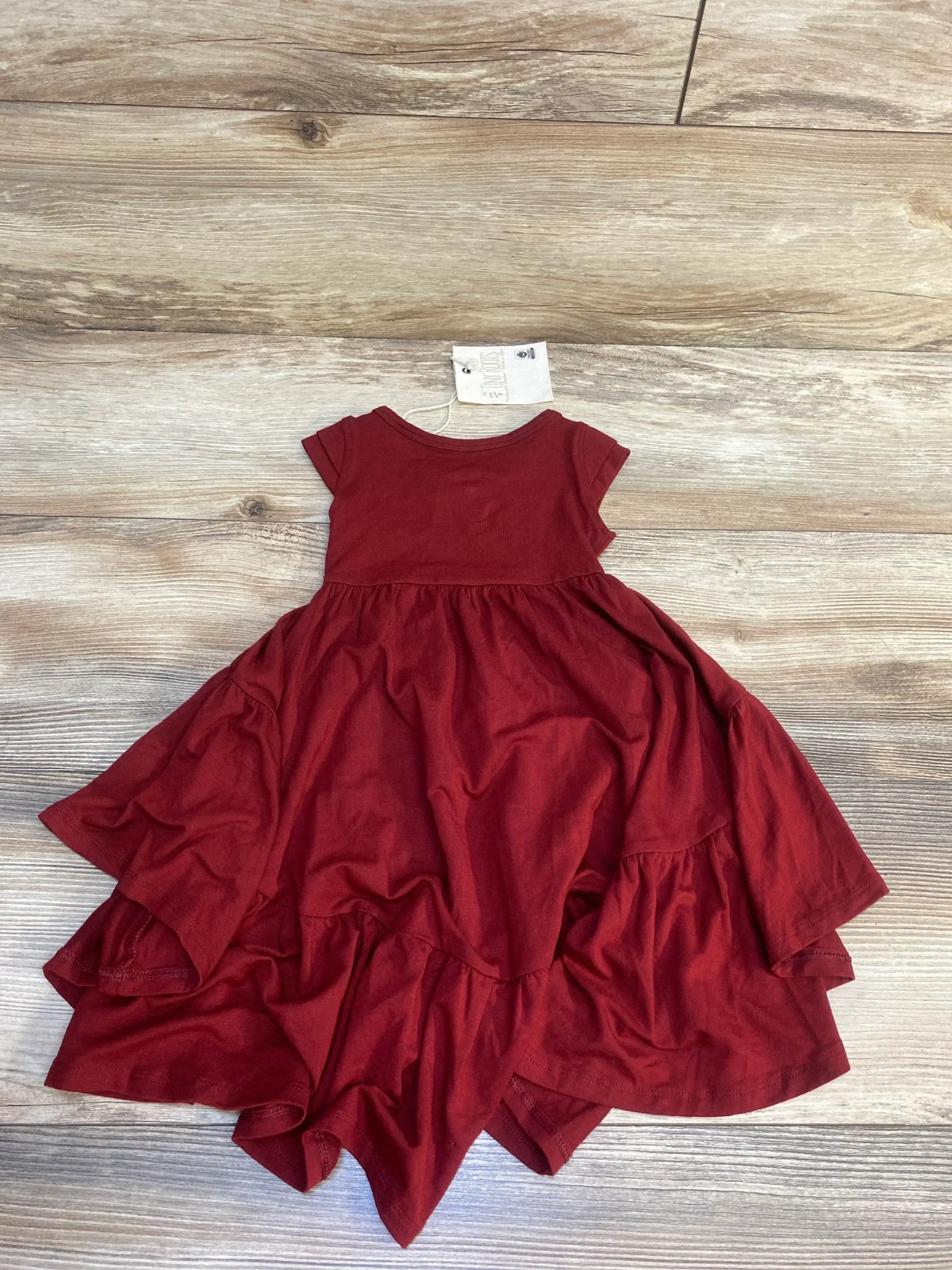 Burgundy girls' short sleeve dress with layered ruffle skirt displayed on wood floor
