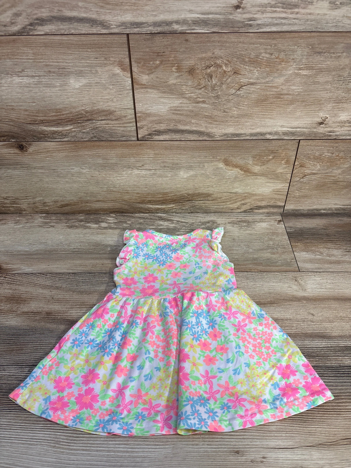 Flat lay of girls Freestyle floral dress showing ruffled cap sleeves and full gathered skirt on wooden floor