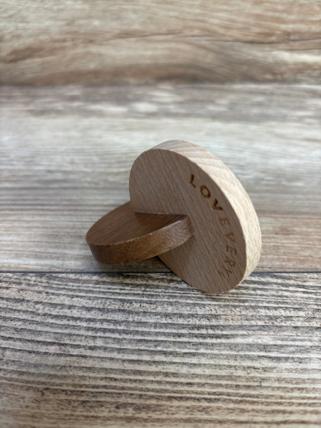 Wooden Montessori disc toy engraved with LOVEVERY on woodgrain background