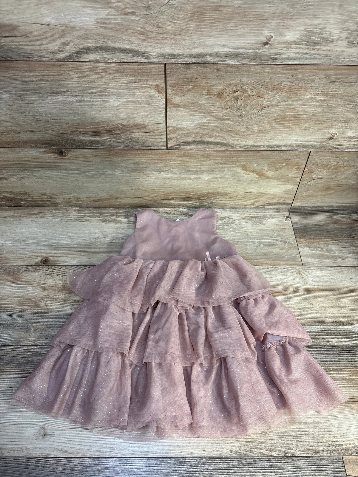 Front view of H&M sleeveless layered tulle dress in pink, size 2T, showcasing tiered tulle layers on a wood-look floor