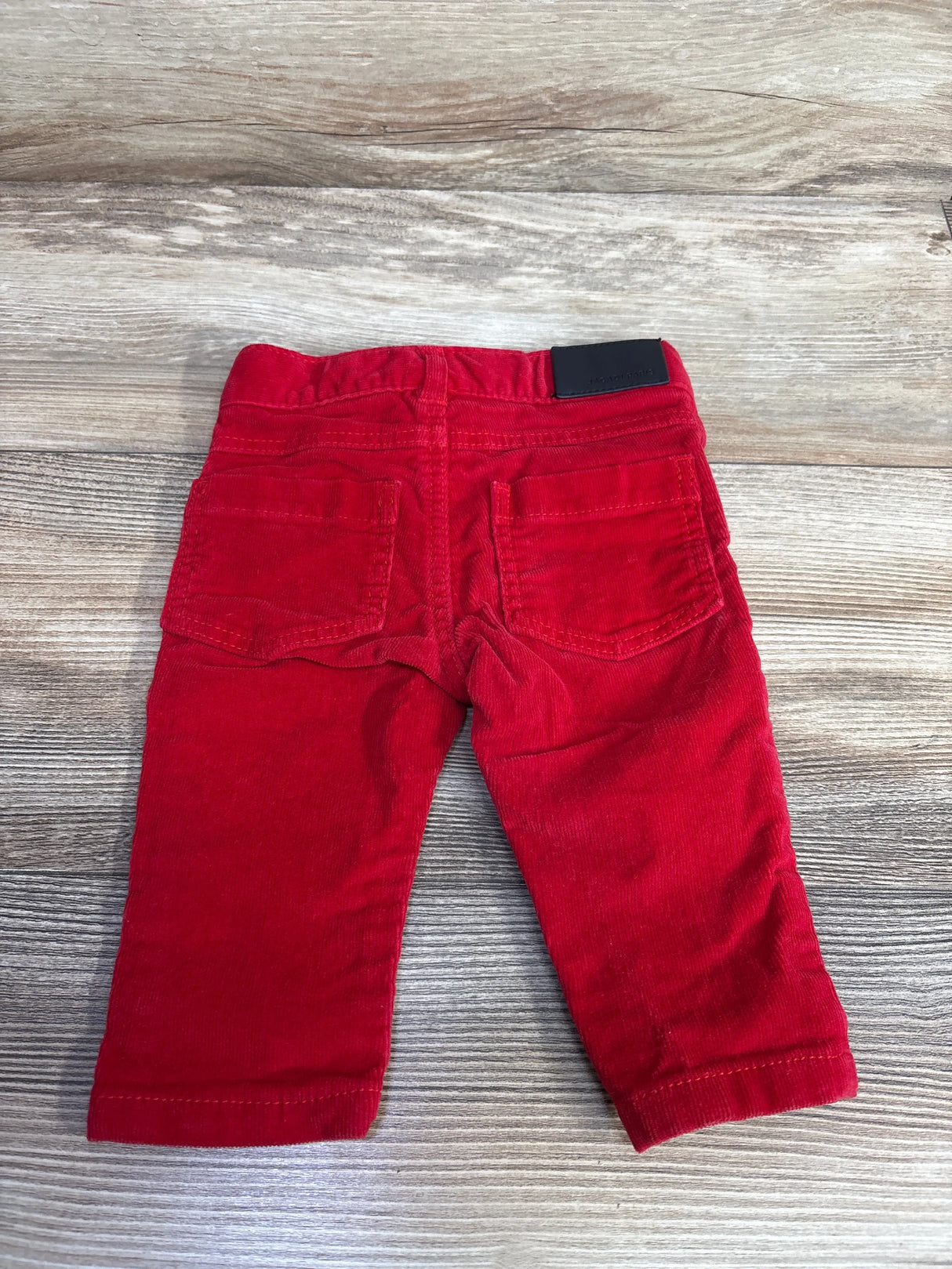Red corduroy toddler pants with back pockets on wood background