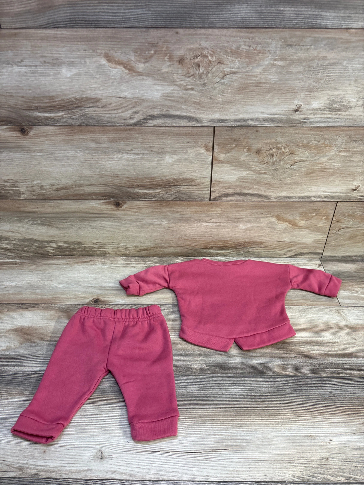 Flat-lay back view of Minnie Mouse 2-piece pink sweatshirt and joggers showing elastic waist and cuffed ankles on wood backdrop