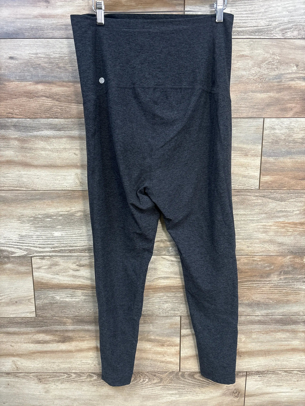 Front view of Zella maternity leggings size Large in dark gray showing high-rise maternity panel and tapered full-length legs against wood background