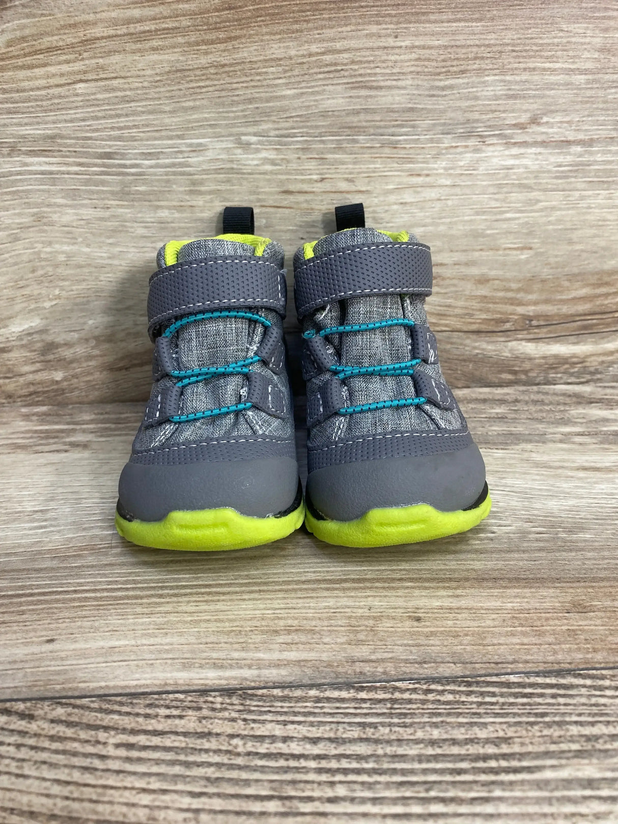 Front view of See Kai Run Sam II boots, waterproof, gray uppers, lime soles, teal elastic laces and Velcro on wood background
