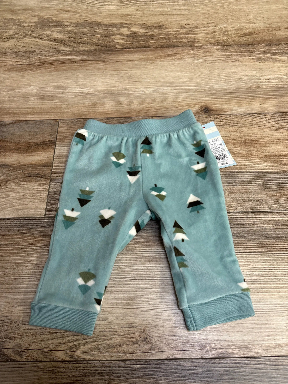 Soft teal baby pants with tree pattern on wood floor, resale kids clothing