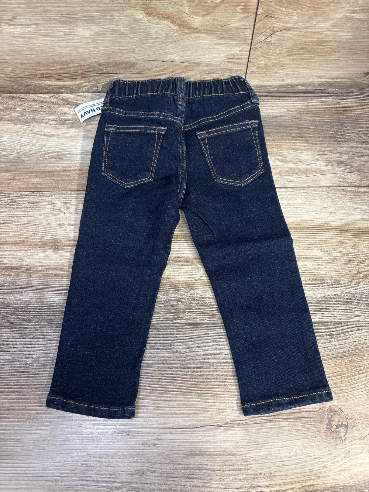 Dark wash toddler jeans with elastic waistband and back pockets on wood background