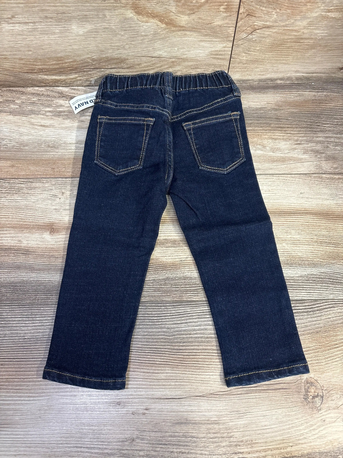 Dark wash toddler jeans with elastic waistband and back pockets on wood background
