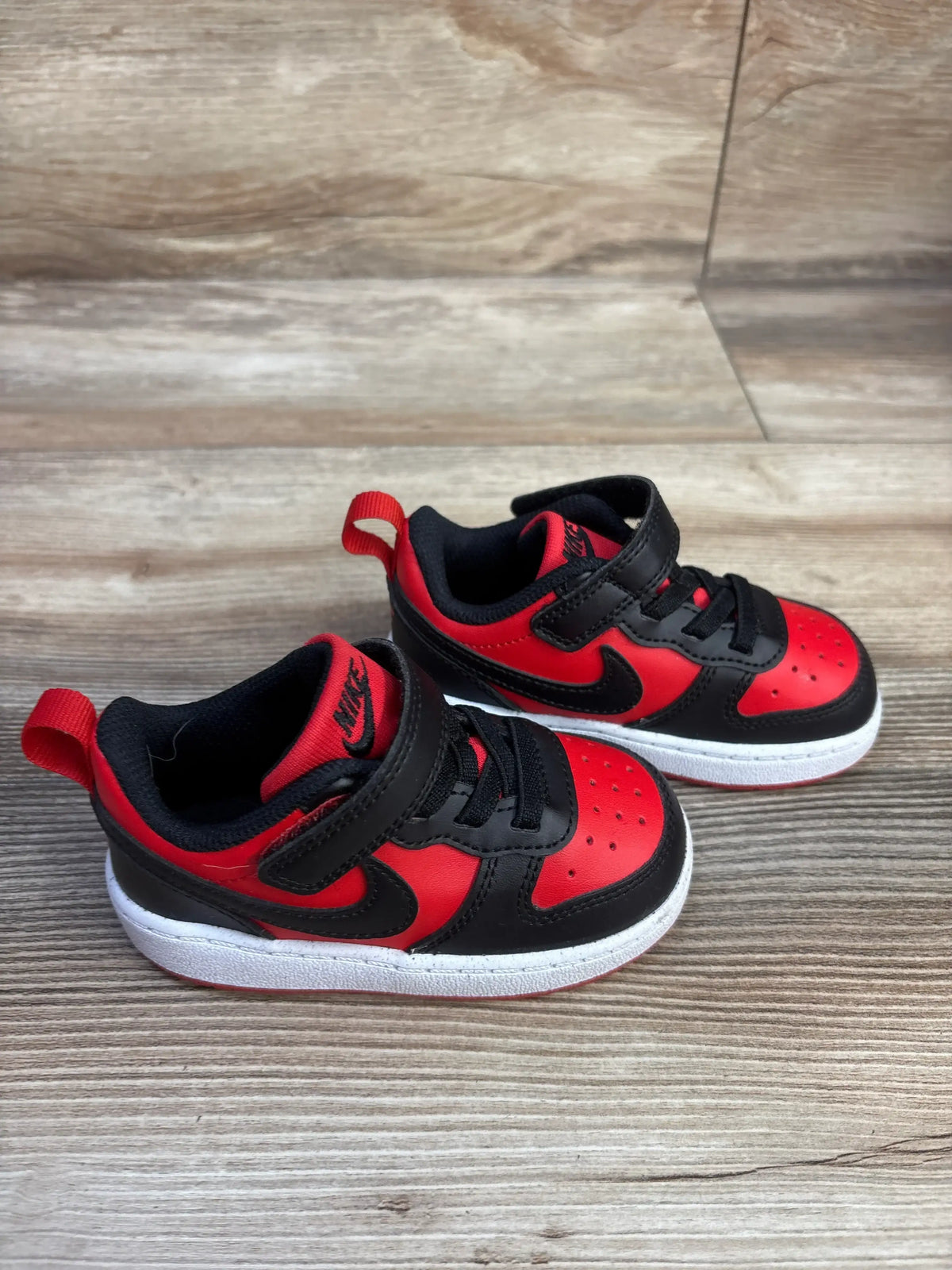 Close view of Nike Court Borough Recraft TD sneakers showcasing University Red and Black uppers, black swooshes, and white midsoles