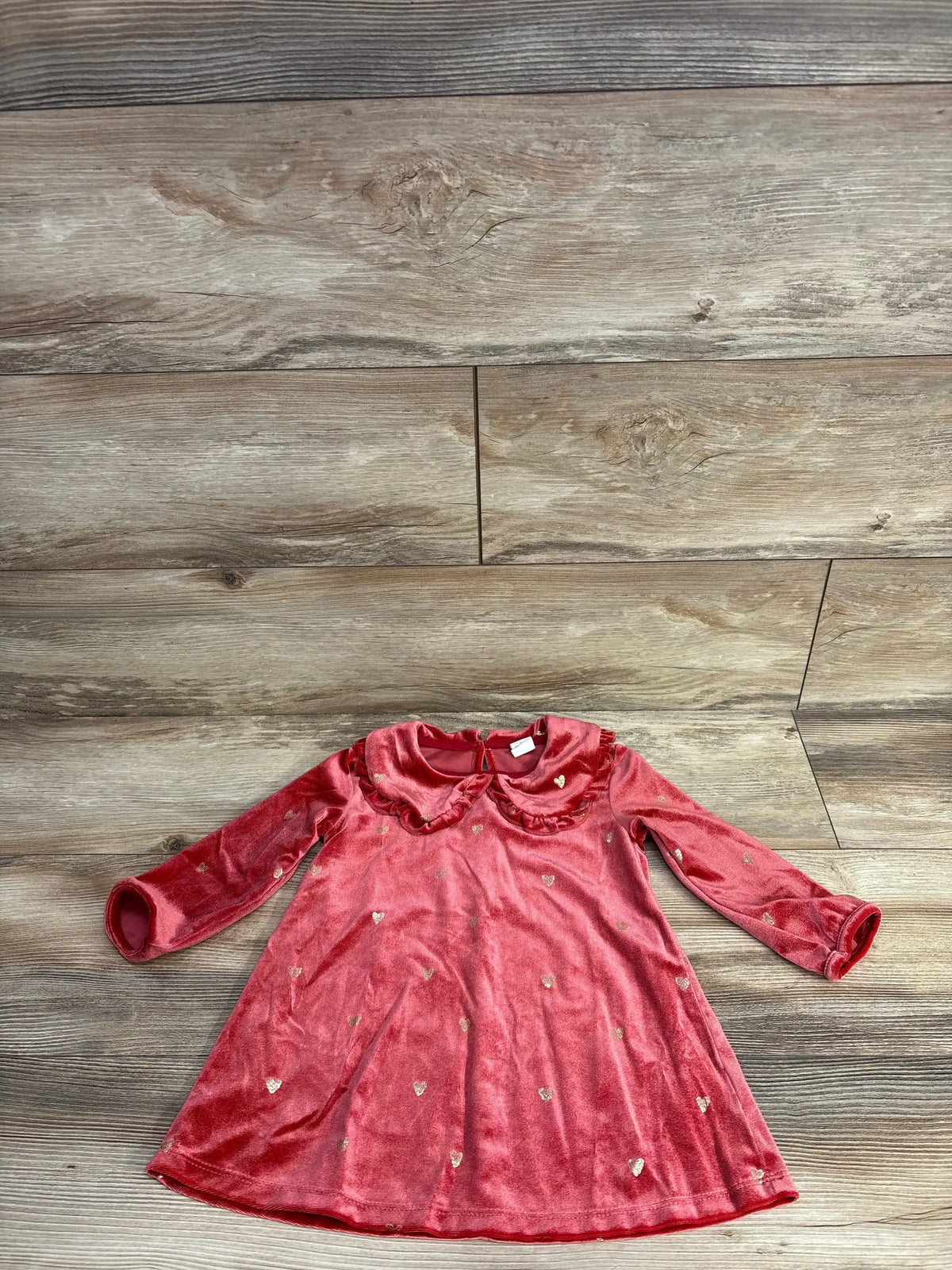 Red velvet long-sleeve baby dress with ruffled collar and gold heart print on wooden floor