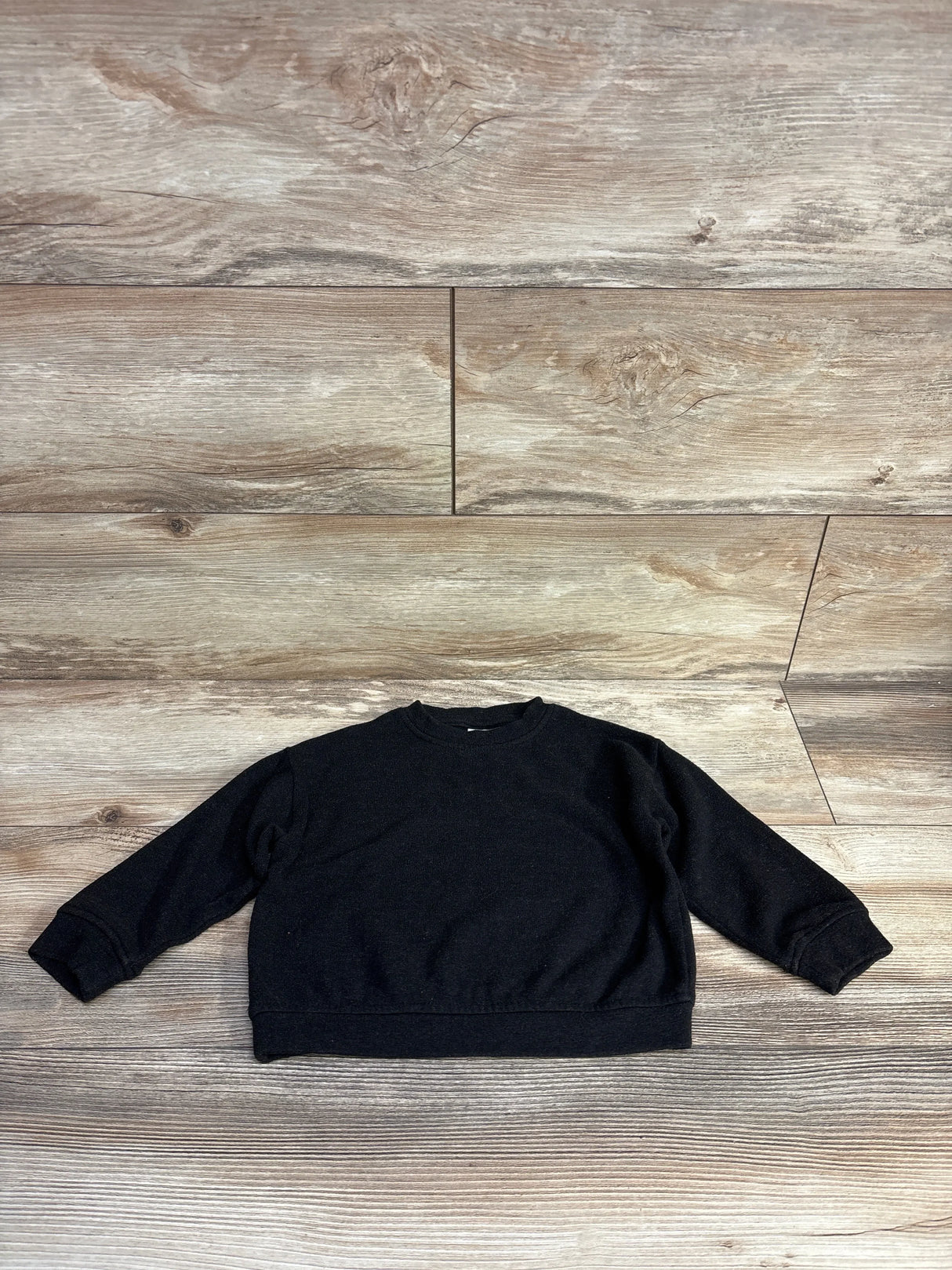 Black long sleeve toddler sweatshirt on wood background, kids clothing resale.
