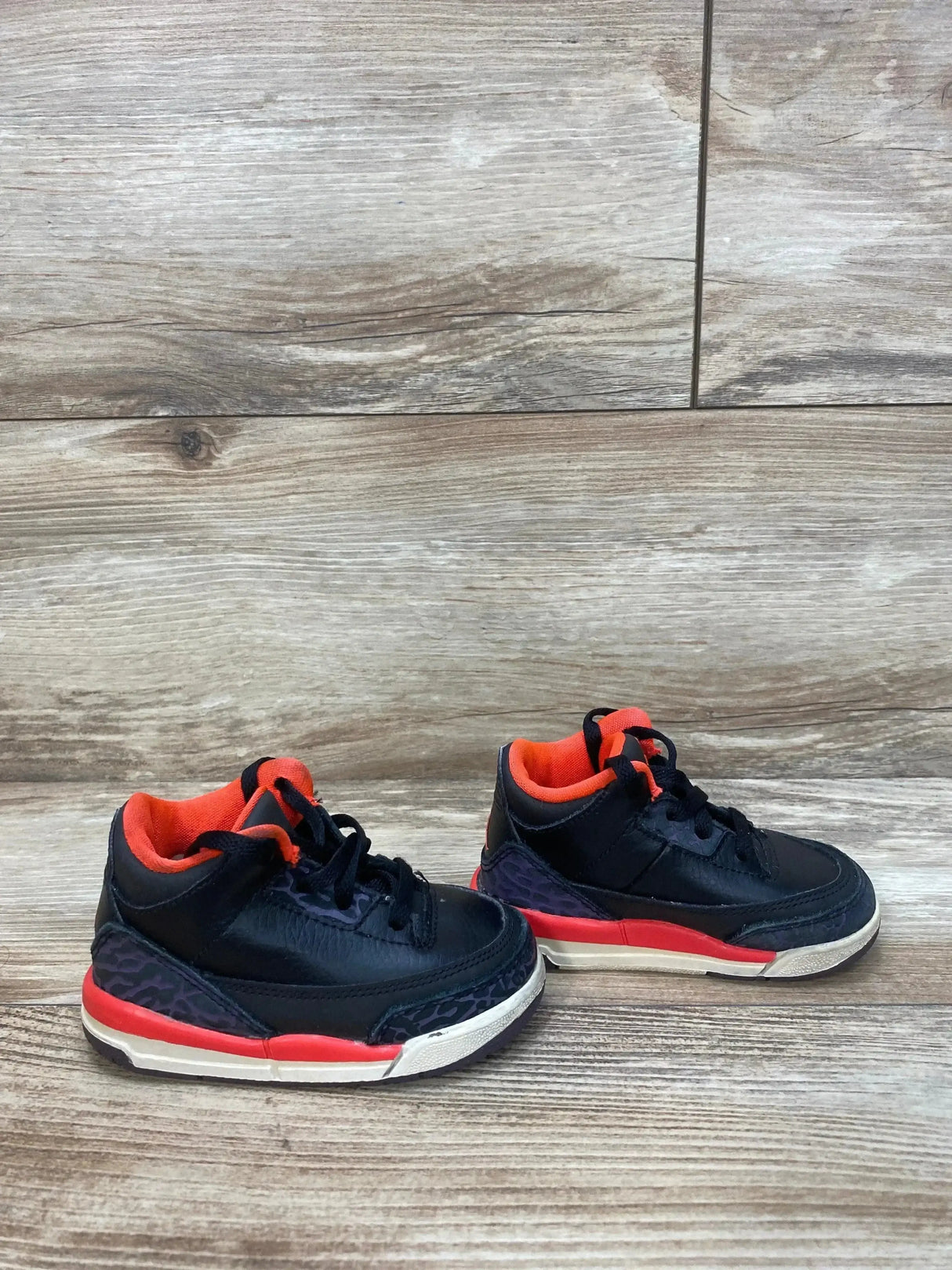 Front view of Jordan Black Crimson Air Jordan 3 Retro TD Sneakers sz 5c with crimson tongue elephant print toe and white midsole on wood plank floor