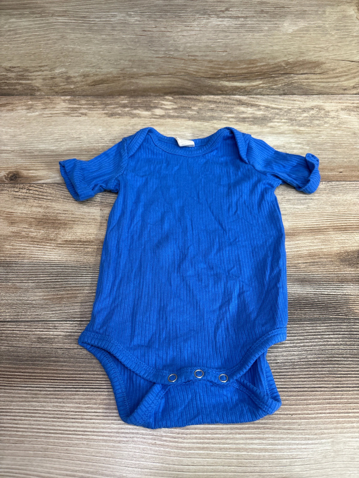 Kate Quinn ribbed modal blue baby bodysuit for 3-6 months on a wooden background