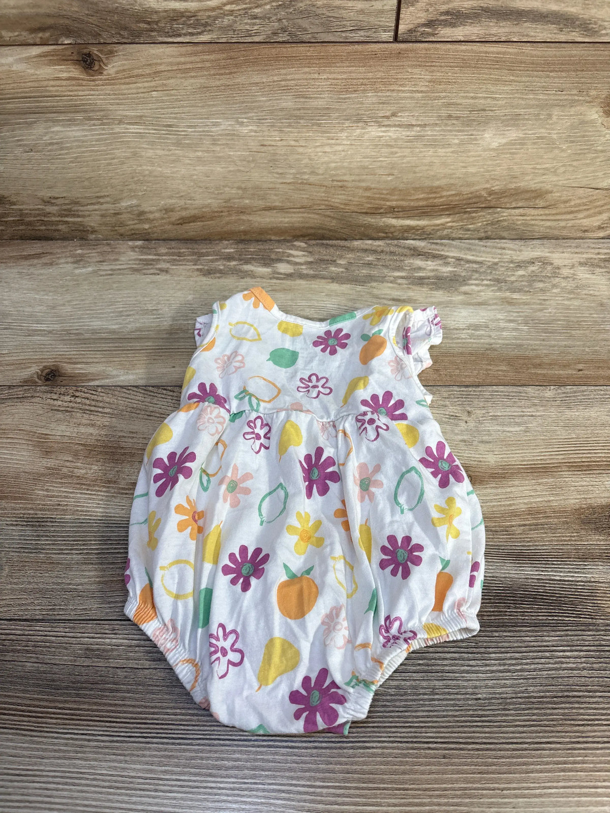 Top view of Okie Dokie white floral bubble romper, size 6 months, showcasing colorful print and bubble hem on wood grain