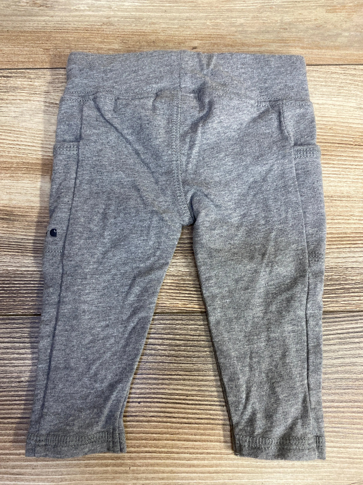 Gray toddler leggings on wooden background, soft cotton baby pants, rear view