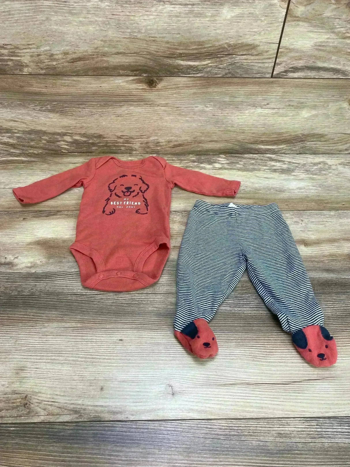 Flat lay of Carter’s 2pc baby set: bodysuit with dog graphic and ‘Best Friend’ text, striped footed pants with dog faces