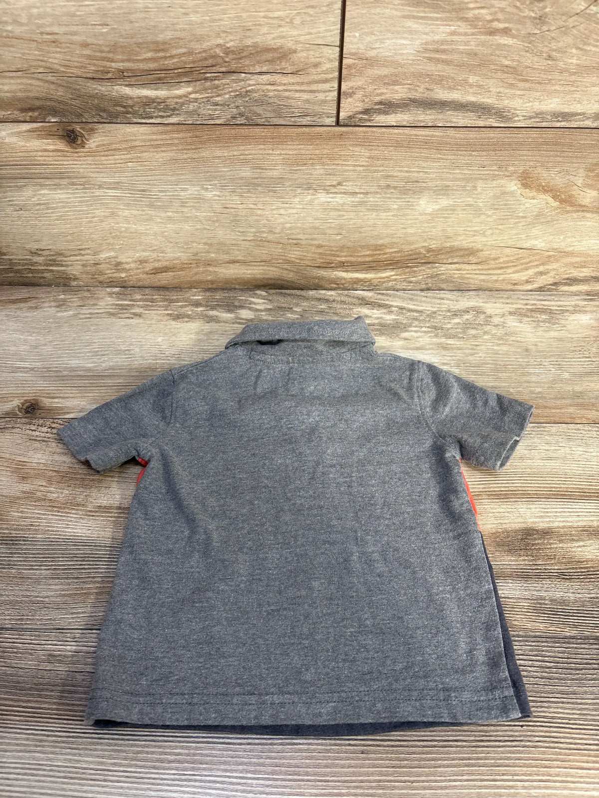 Back view of a grey Jumping Beans polo shirt showcasing its collar and short sleeves on a wood-look background