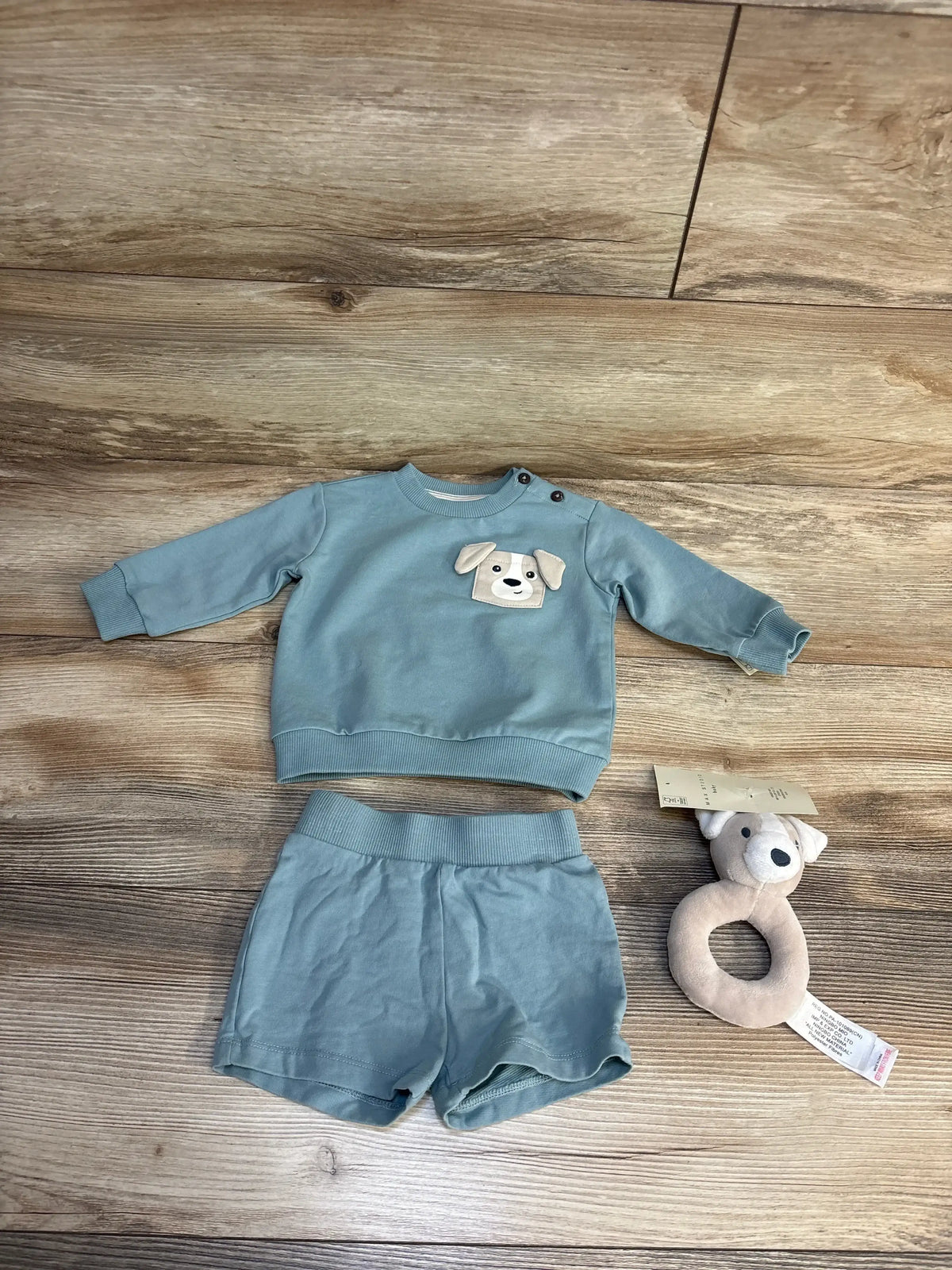 Baby boy outfit with dog appliqué sweater and shorts, plus plush teether toy on wood floor