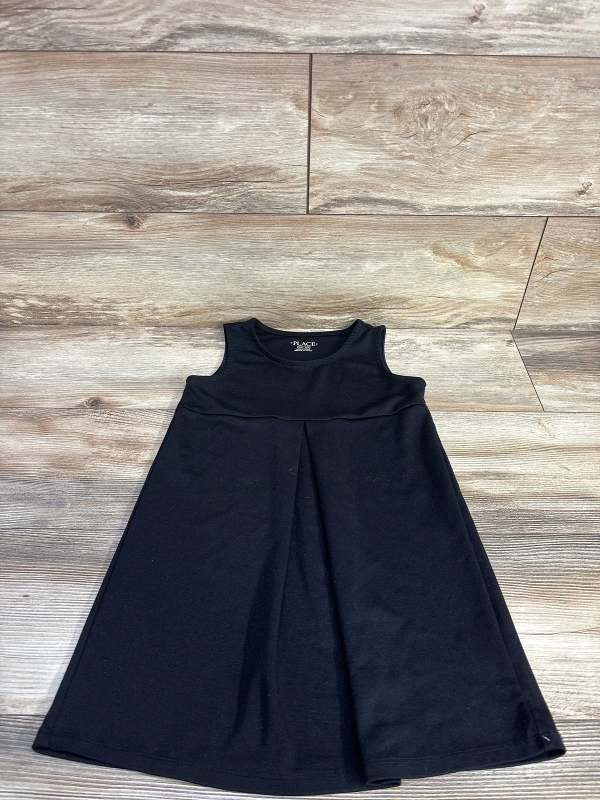 Front view of Children’s Place black unicorn ponte dress in size 5/6T, sleeveless with a flared skirt on wood floor