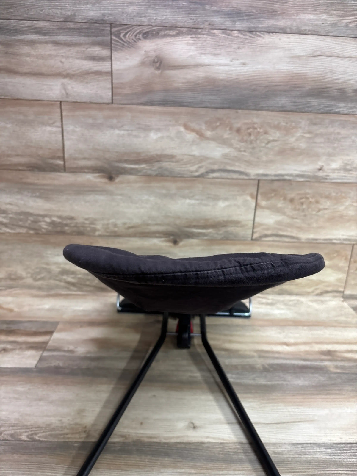 Front view of BabyBjörn Balance Soft Bouncer in Black/Dark Grey showcasing its padded seat and black frame against a wood plank background