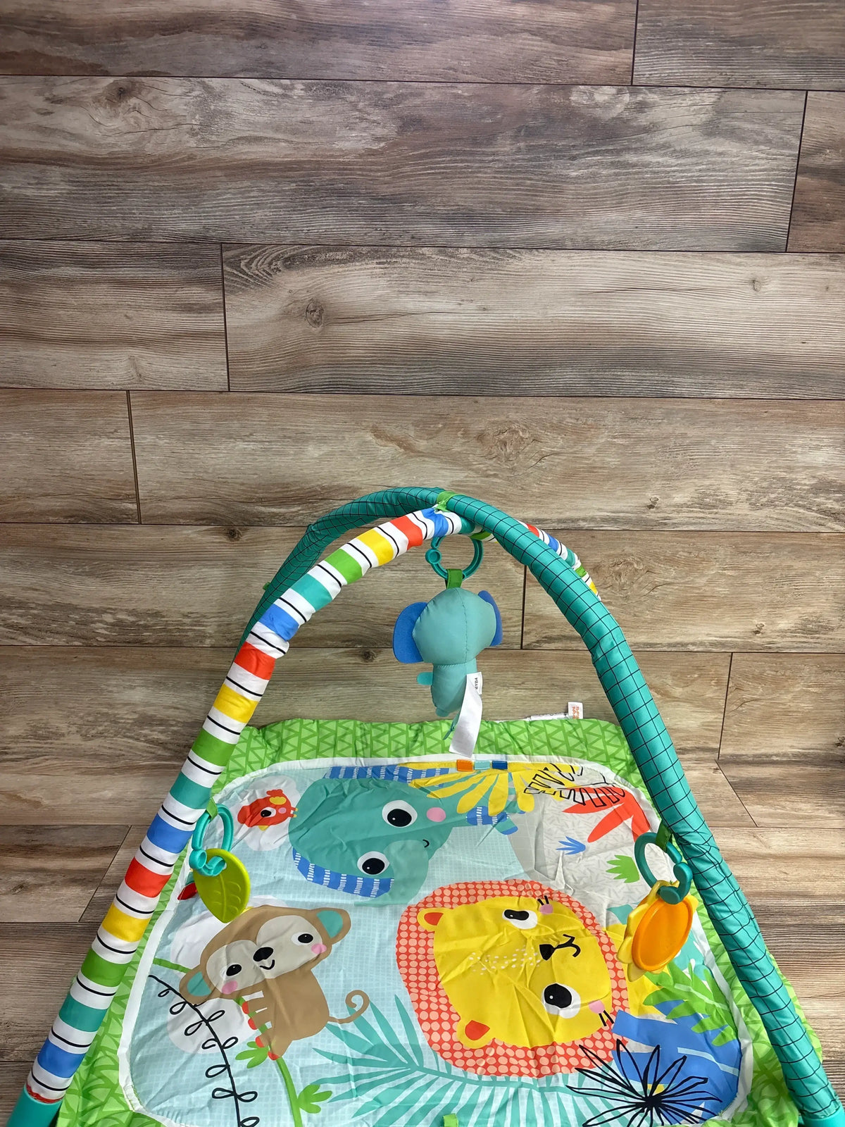 Colorful baby play gym with animal designs including lion, monkey, and elephant on wood floor