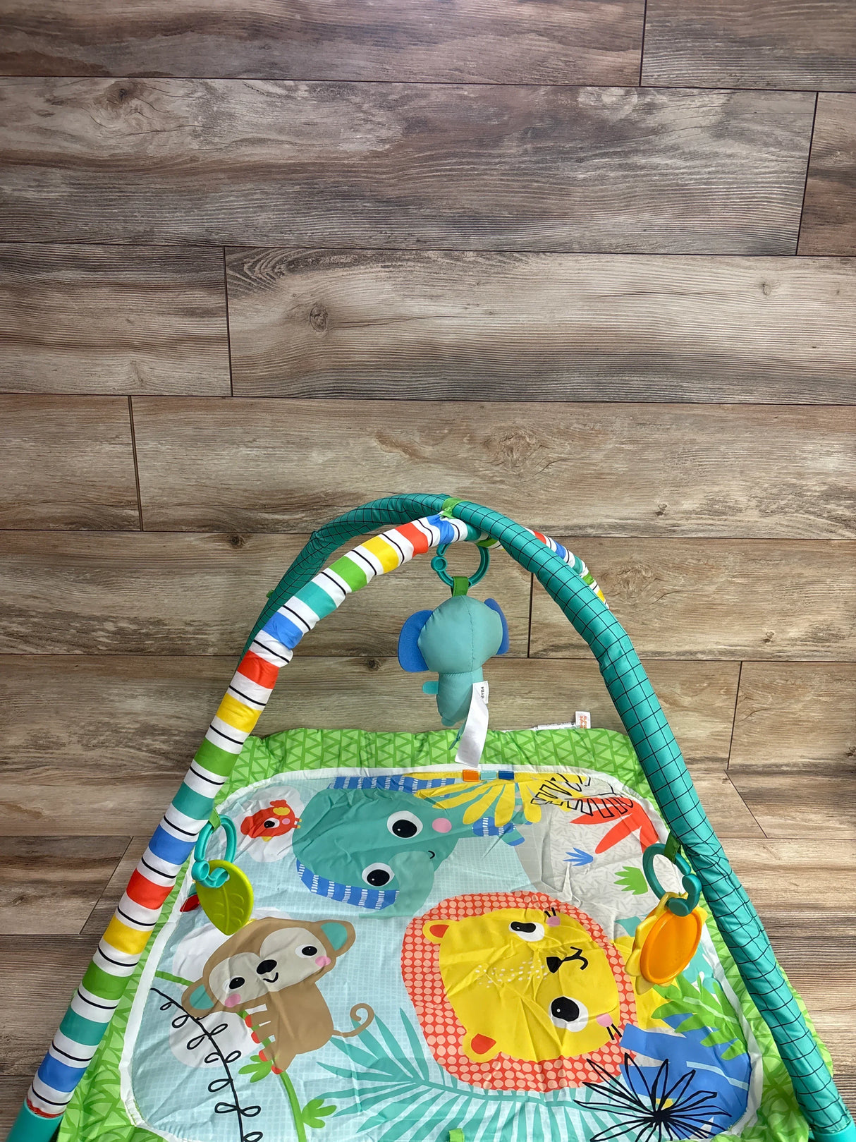 Colorful baby play gym with animal designs including lion, monkey, and elephant on wood floor
