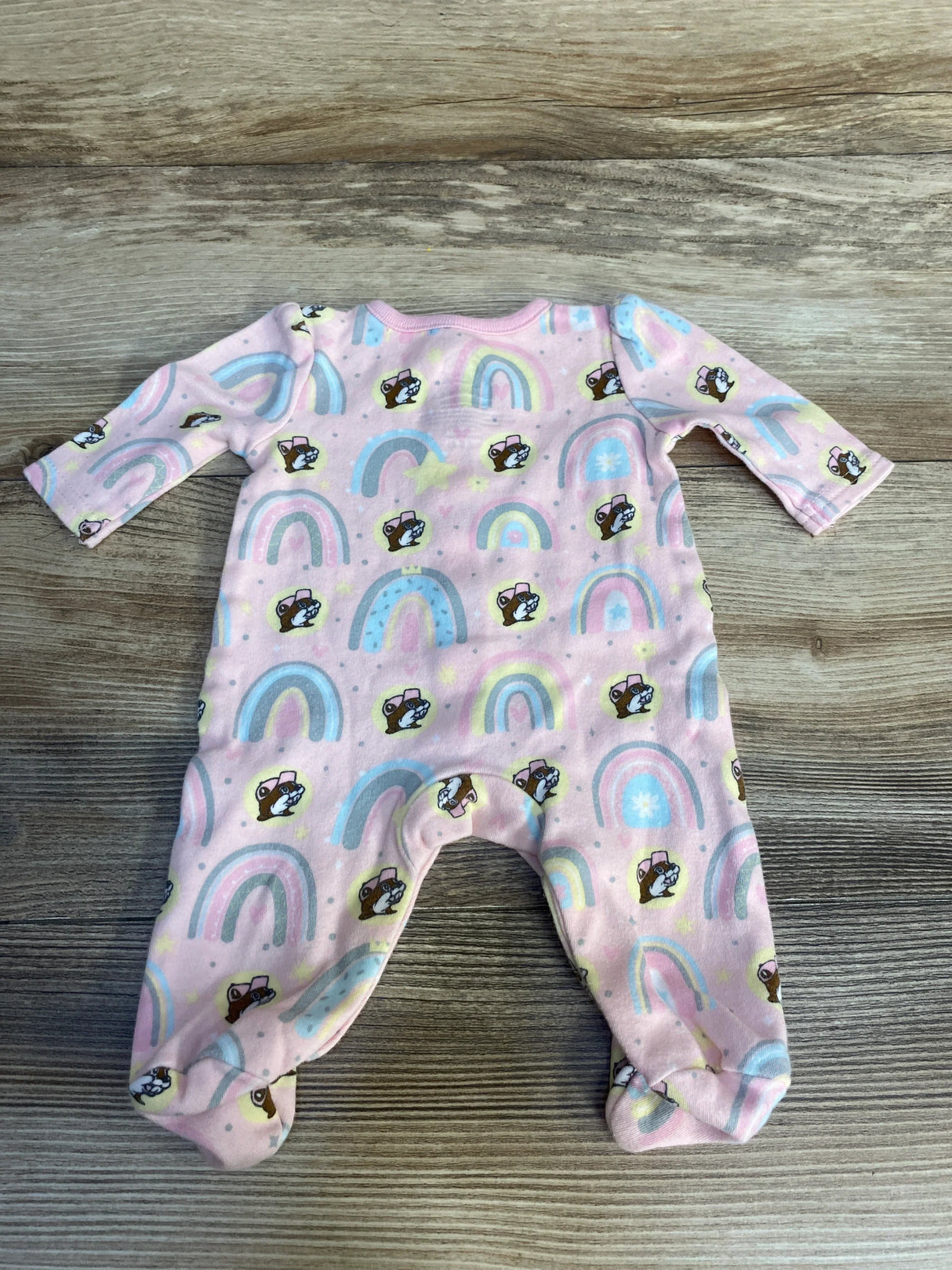 Pink baby footed sleeper with rainbow and cartoon animal print on wood background