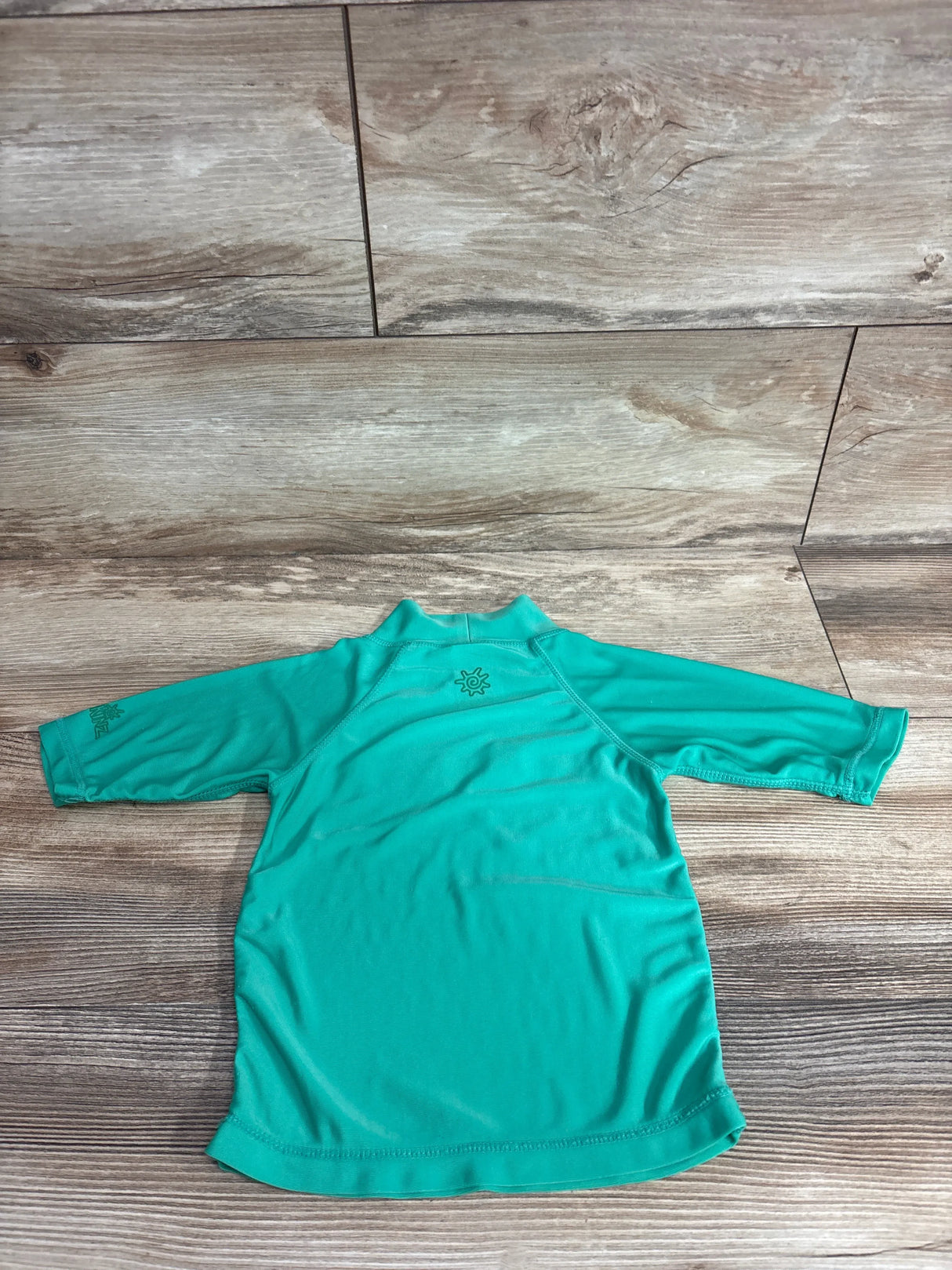 Back view of green UV Skinz Frog Rash Guard Shirt showcasing long sleeves on wood flooring