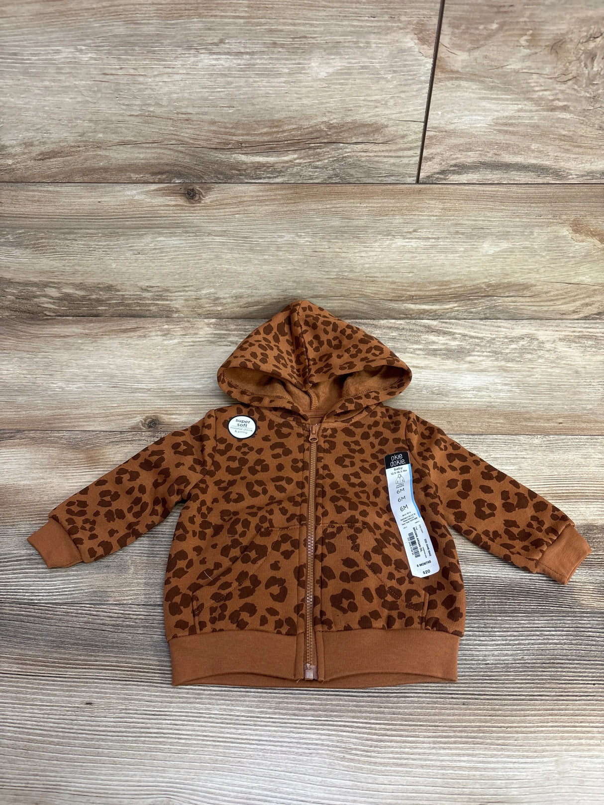 Infant brown leopard print hooded zip-up jacket with tags, laid on wood floor