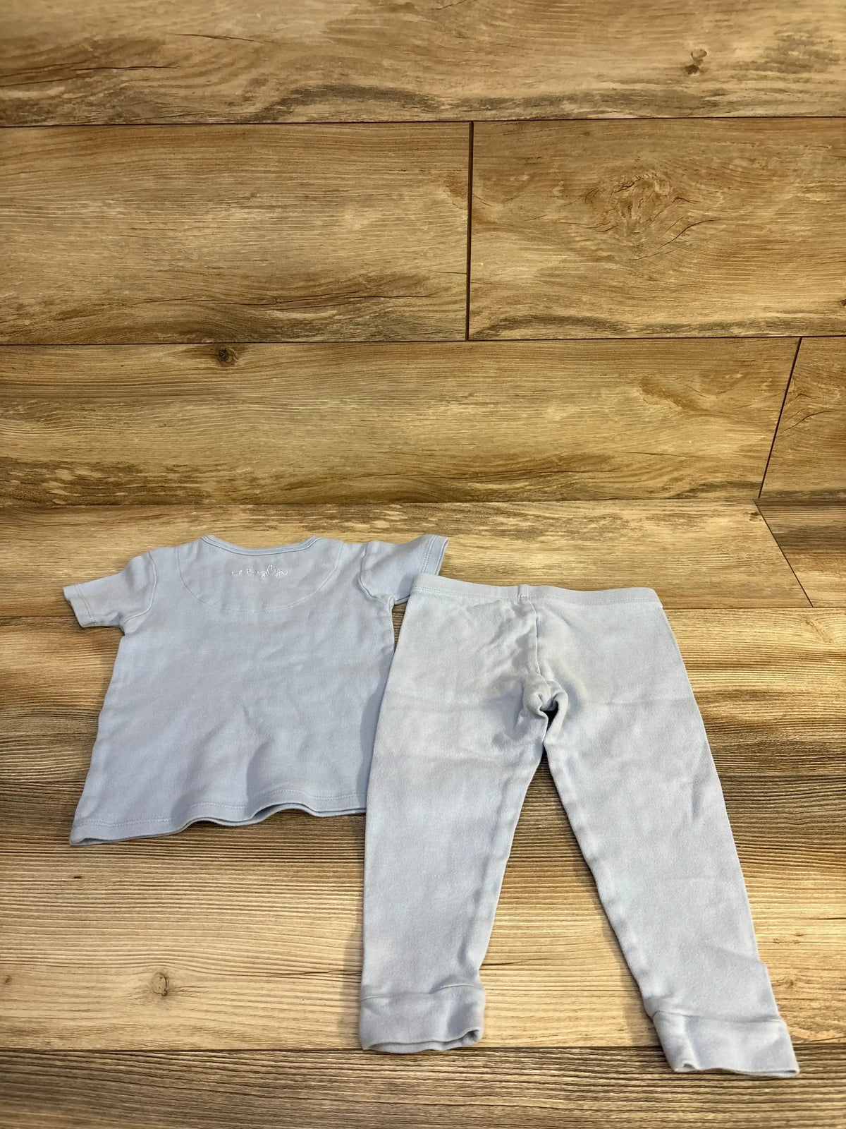 Flat lay of Magnetic Me Simply two piece blue toddler pajama set showing short sleeve top and full length pants on wood floor background