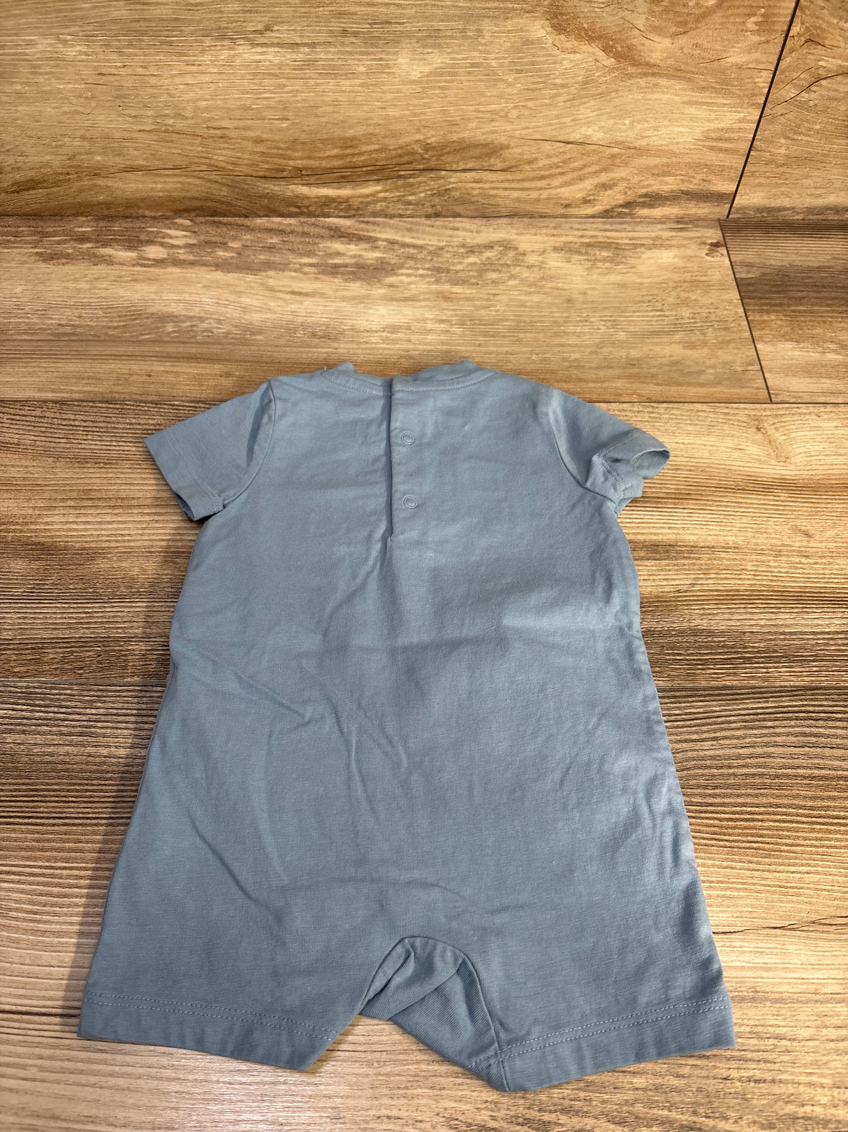 Back view of Ralph Lauren blue short-sleeve soft cotton shortie romper showing two back snaps and crotch snaps on wood floor