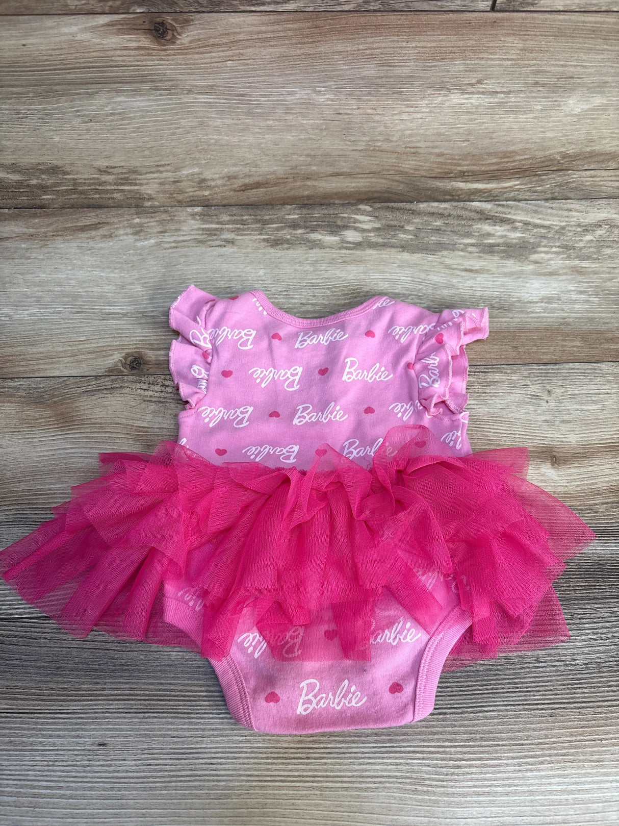 Pink Barbie baby onesie with ruffled tutu skirt, perfect for little girls' dress-up