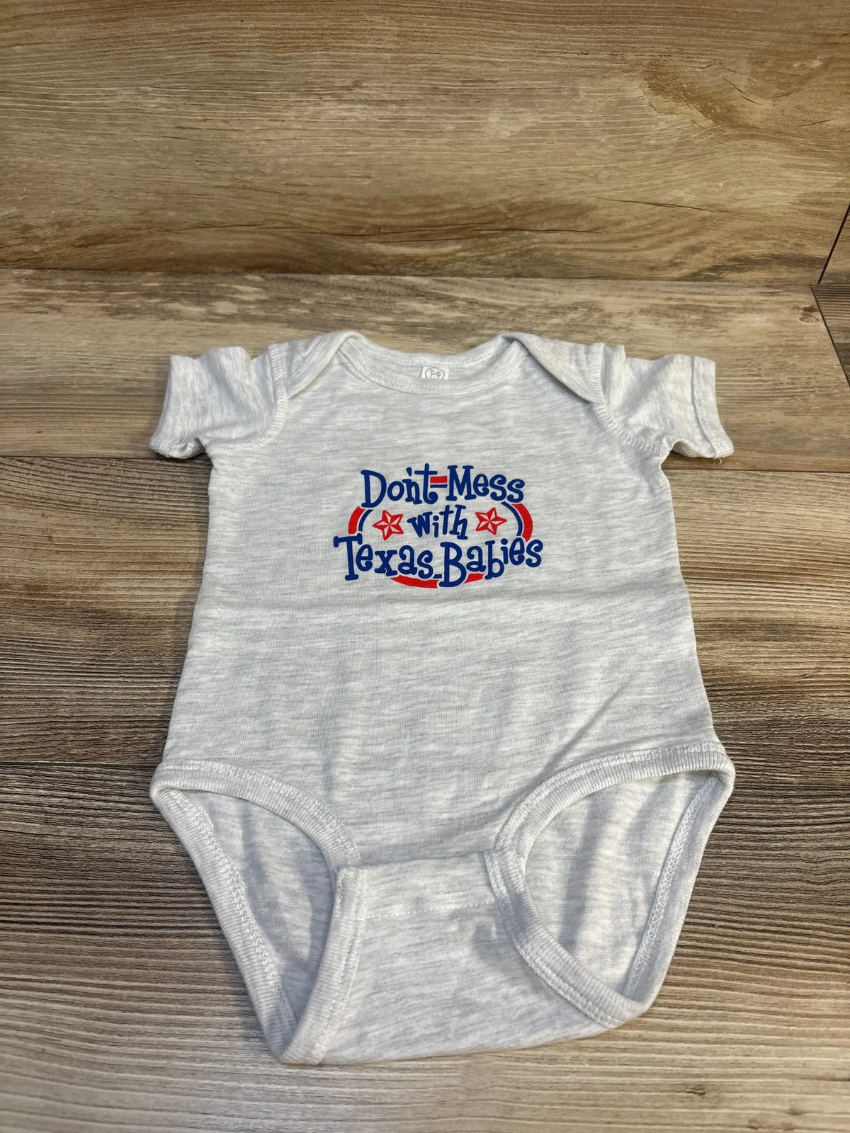 Front view of grey Rabbit Skins bodysuit showcasing black Don’t Mess With Texas Babies chest print on white background