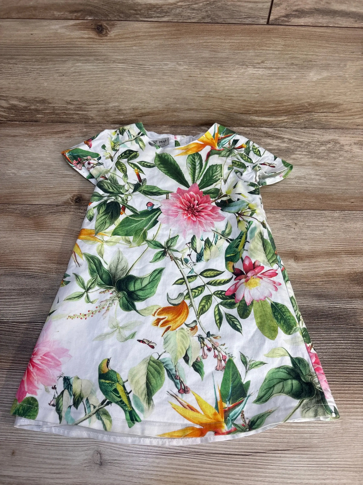 Toddler short sleeve dress with colorful tropical floral and bird print on wood floor