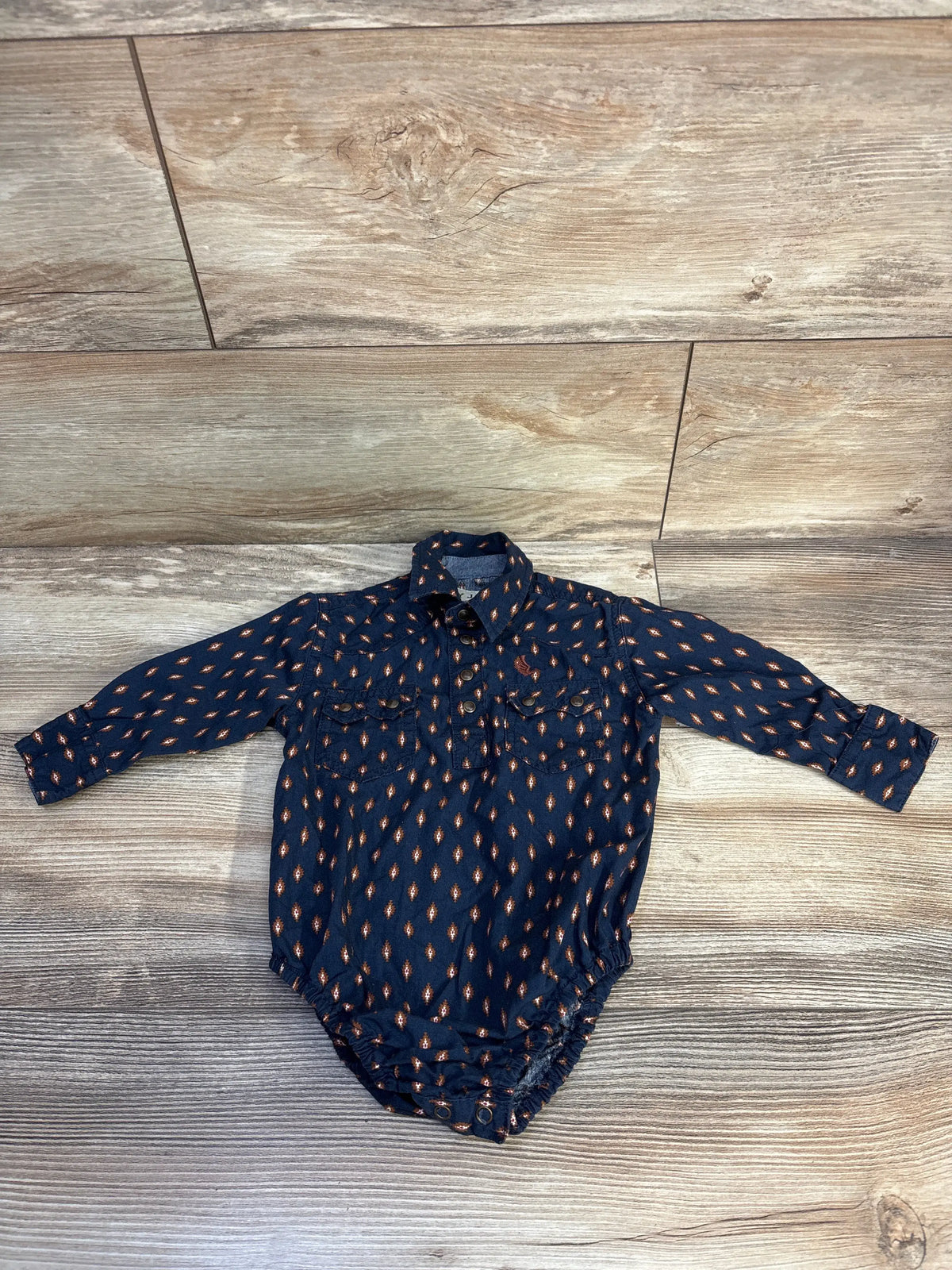 Front view of Cody James navy polo bodysuit with patterned long sleeves, polo collar, and button front on wood look flooring