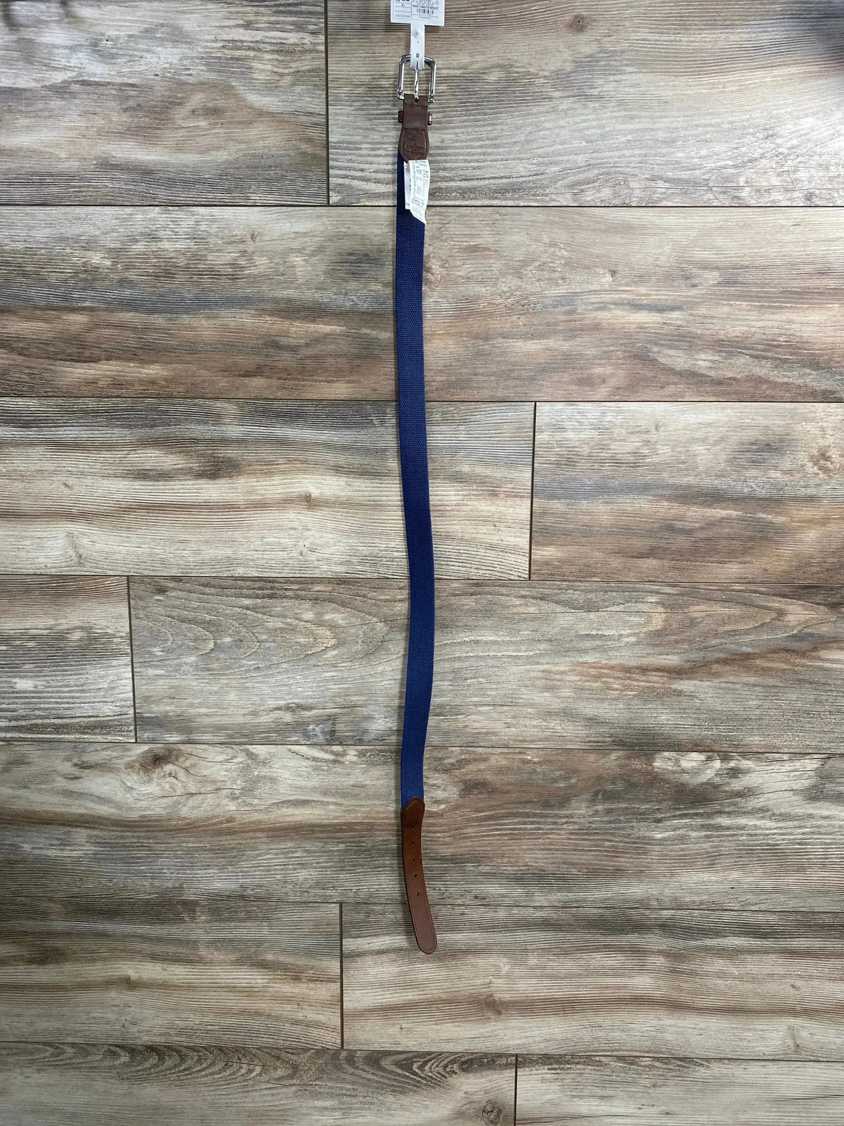 Full-length front view of Cat & Jack chambray blue belt showing woven strap, brown leather ends and silver buckle on wood floor