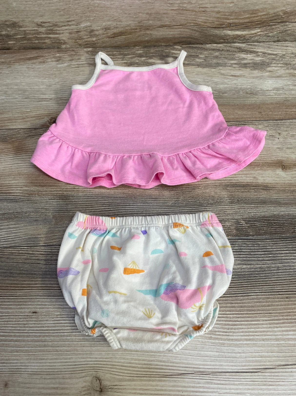 Flat lay of Cat & Jack baby set: pink ruffle-hem tank and printed bloomers with elastic waist on wood background