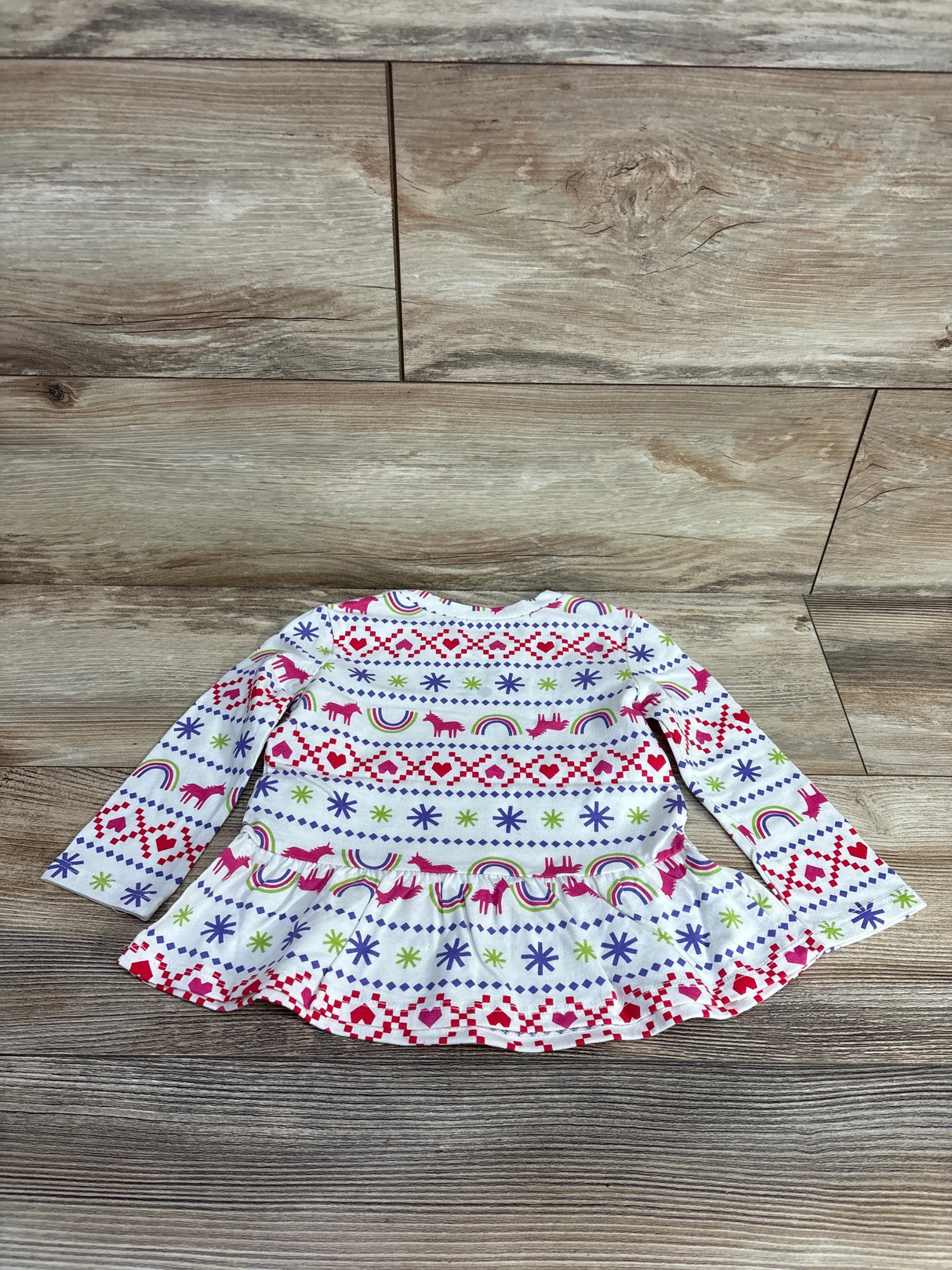 Toddler long-sleeve white dress with colorful hearts, unicorns, rainbows, and snowflake patterns on wooden floor
