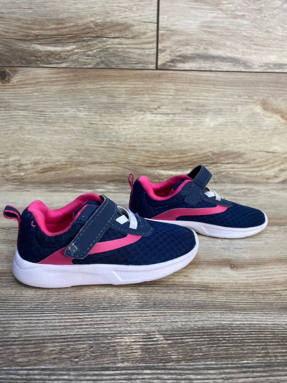 Kids navy blue and pink athletic sneakers with Velcro straps on wood floor