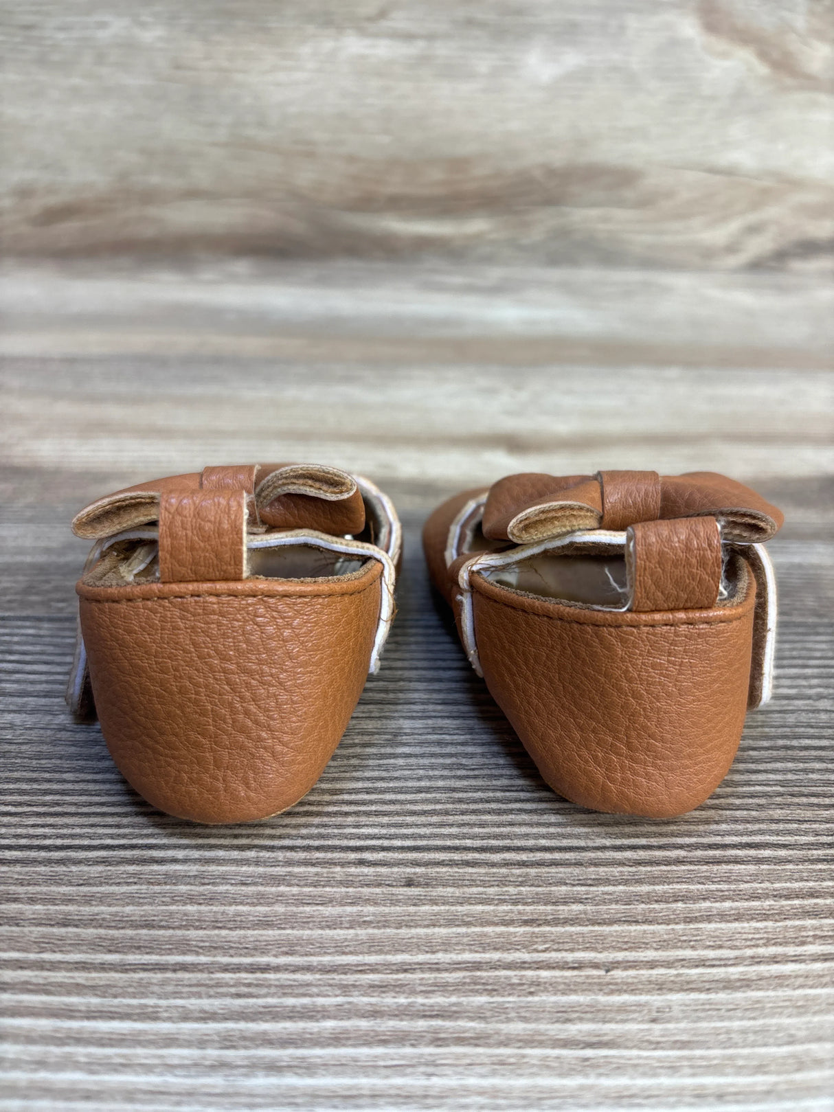 Rear view of Nuby Anti-Slip First Walking Shoes Brown sz 2c showcasing Mary jane velcro straps on a wooden background