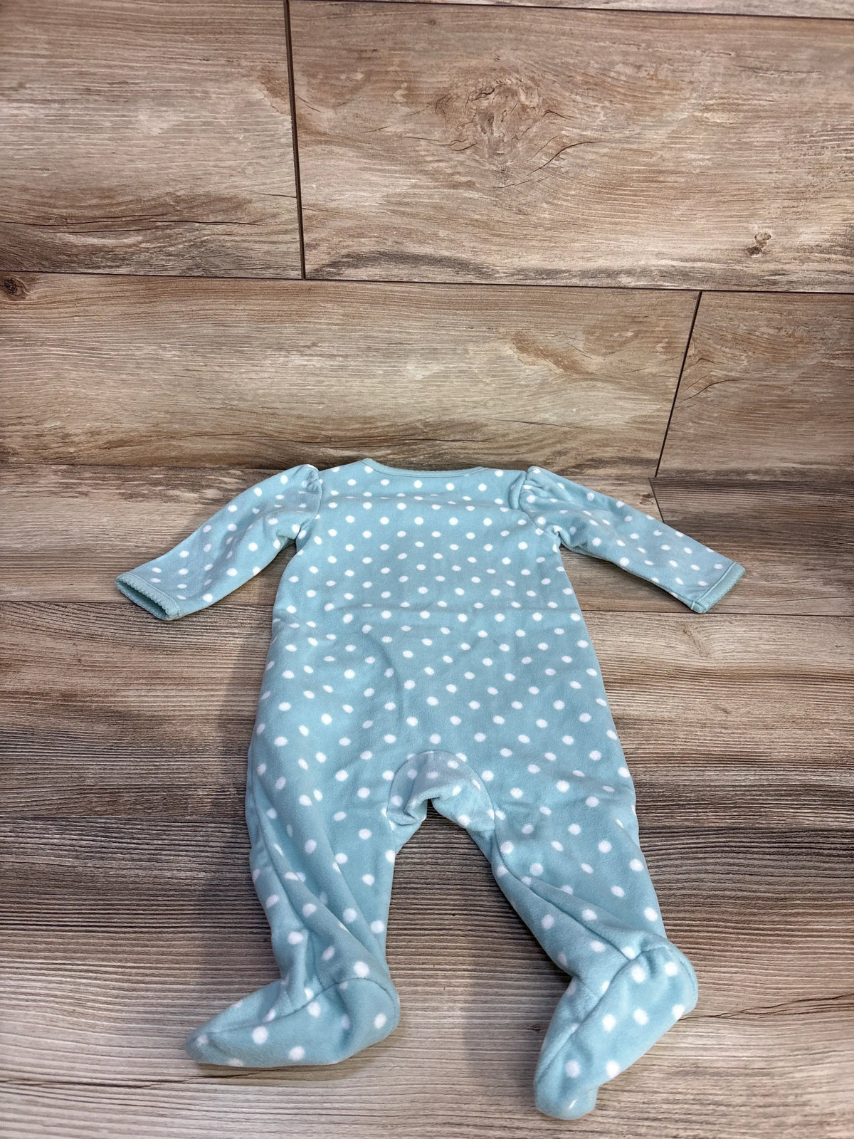 Front view of Simple Joys teal blanket sleeper with white polka dots, long sleeves, and covered feet on a wood floor