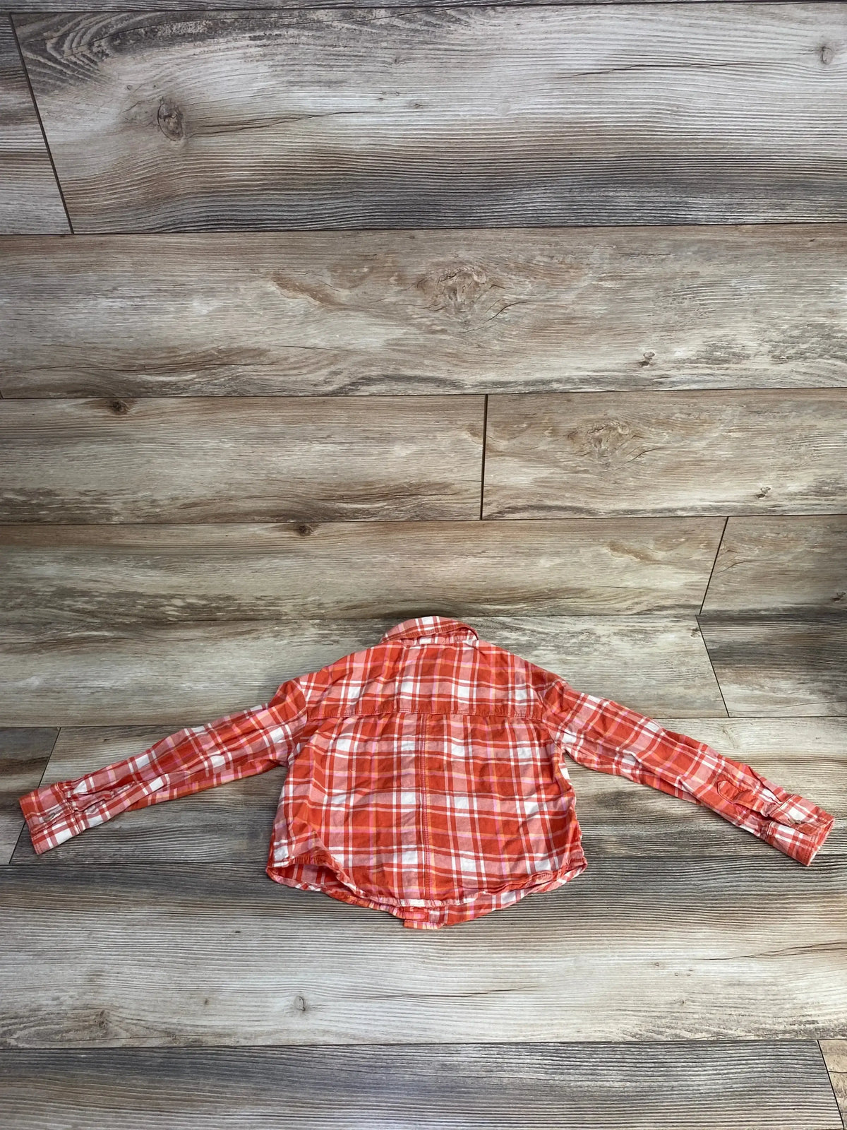 Back view of Cat & Jack orange plaid button-up flannel toddler shirt, size 4T, laid flat on rustic wood floor